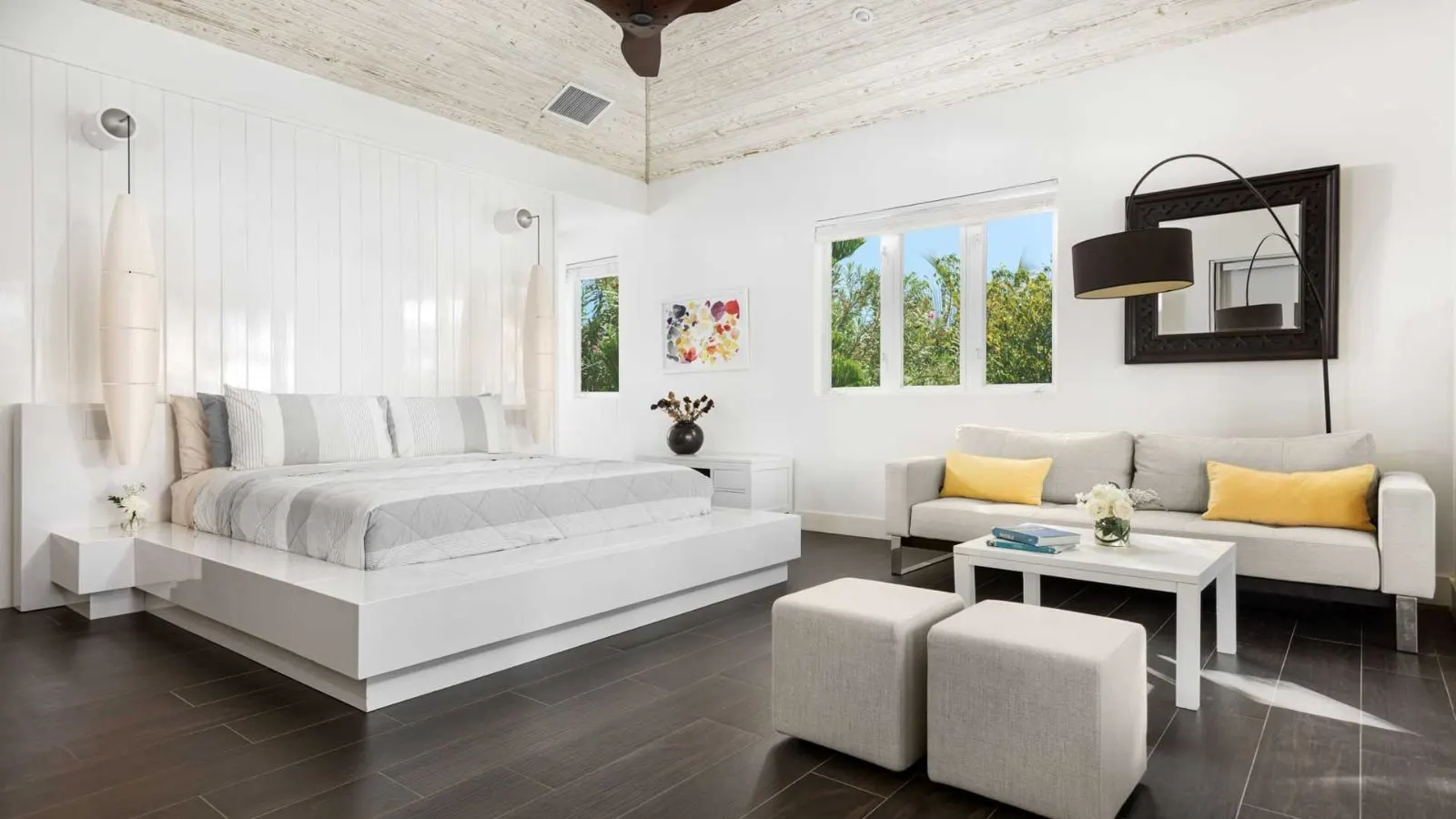 The Master bedroom, king bed, seating area with sofas and a bright garden-view corner.