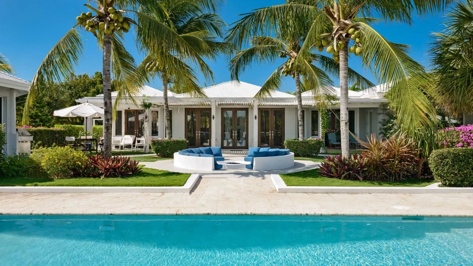 Turks and Caicos villa exterior with sunken garden lounge at golden hour.